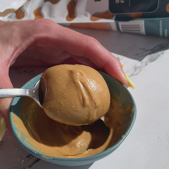 Peanut Butter being poured from a spoon and landing in a peanut butter heap.