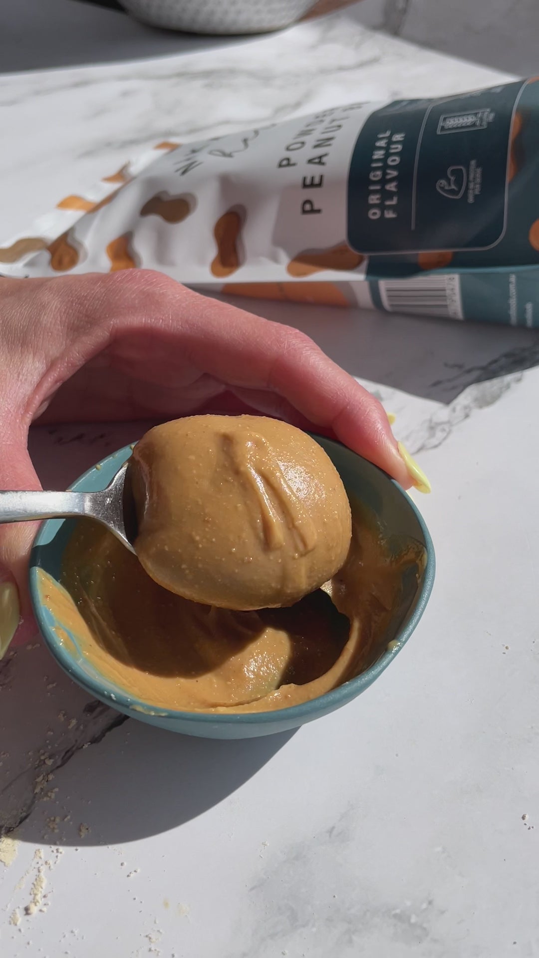 Peanut Butter being poured from a spoon and landing in a peanut butter heap.